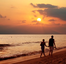 Couple walking along beach at sunset